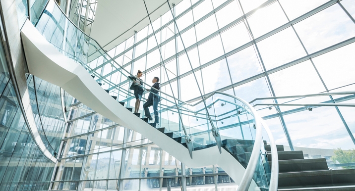 Distant Mixed Race business people standing on staircase and talking