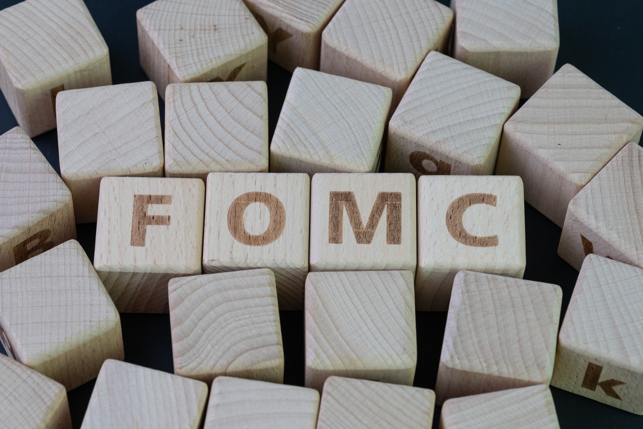 FOMC, Federal Open Market Committee concept, cube wooden block with alphabet building the word FED at the center on dark blackboard background, the institution to control US financial banking.